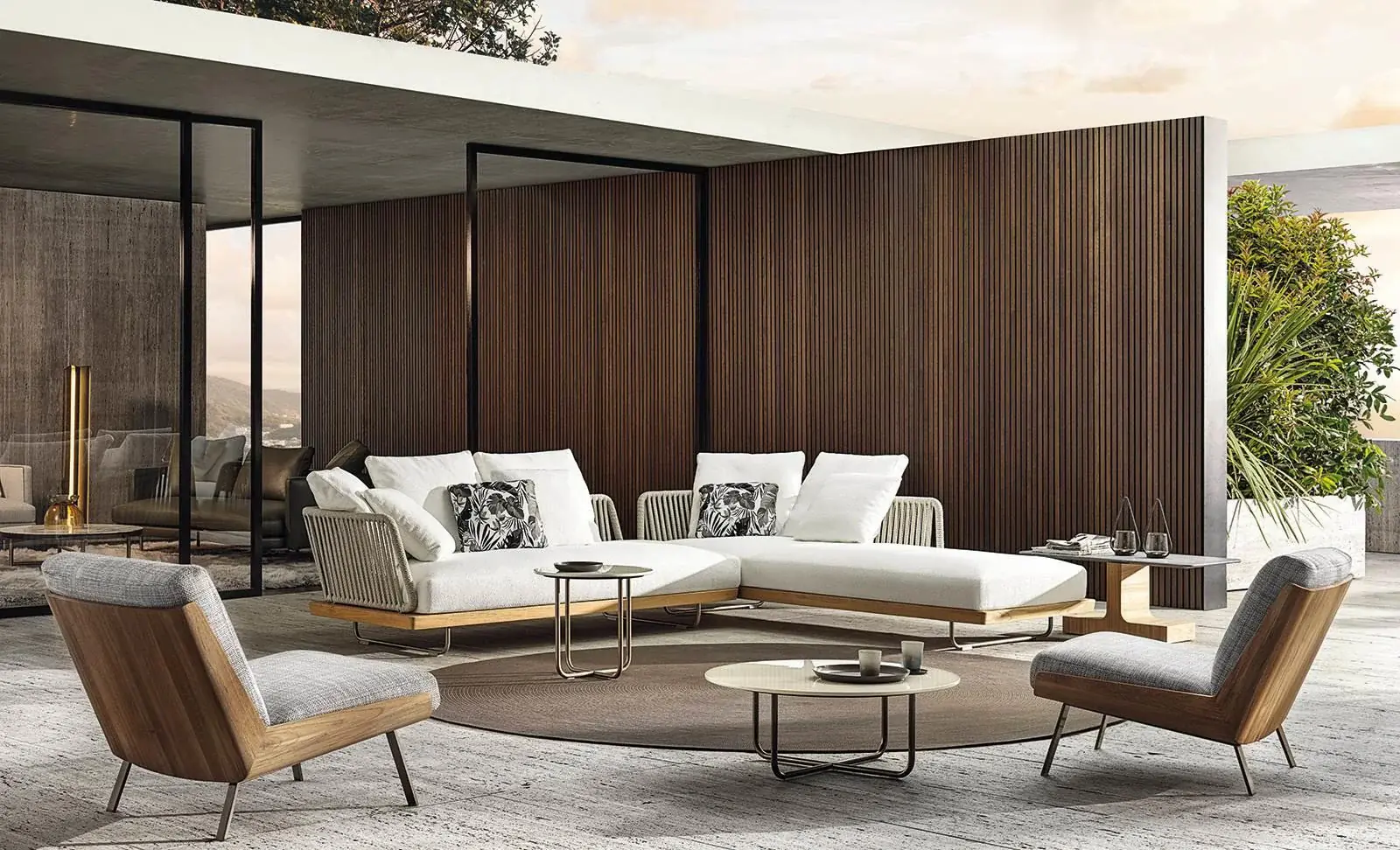 A luxury outdoor space consisting of a sofa, table and two chairs.